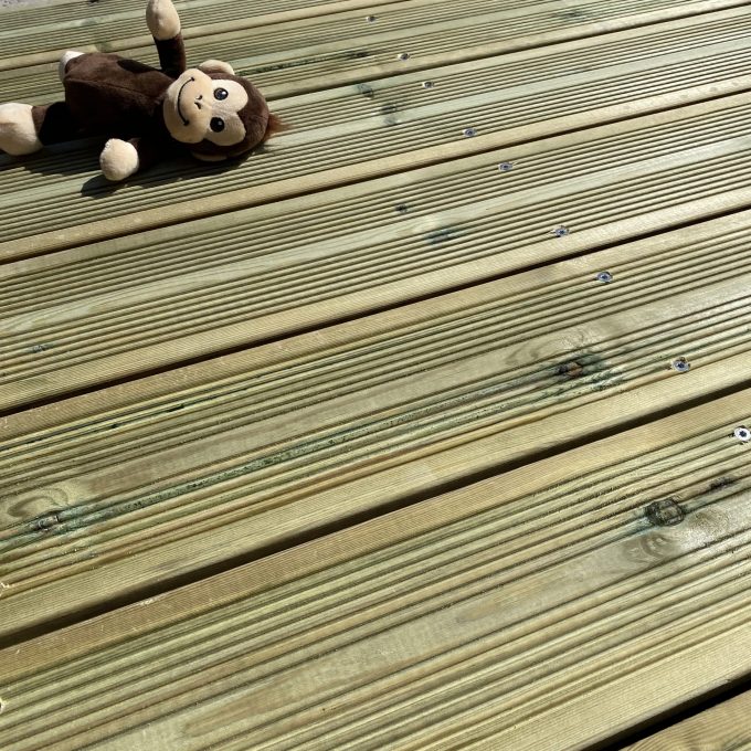 Peluche singe allongé sur une terrasse en lames de pin sylvestre autoclave classe 3