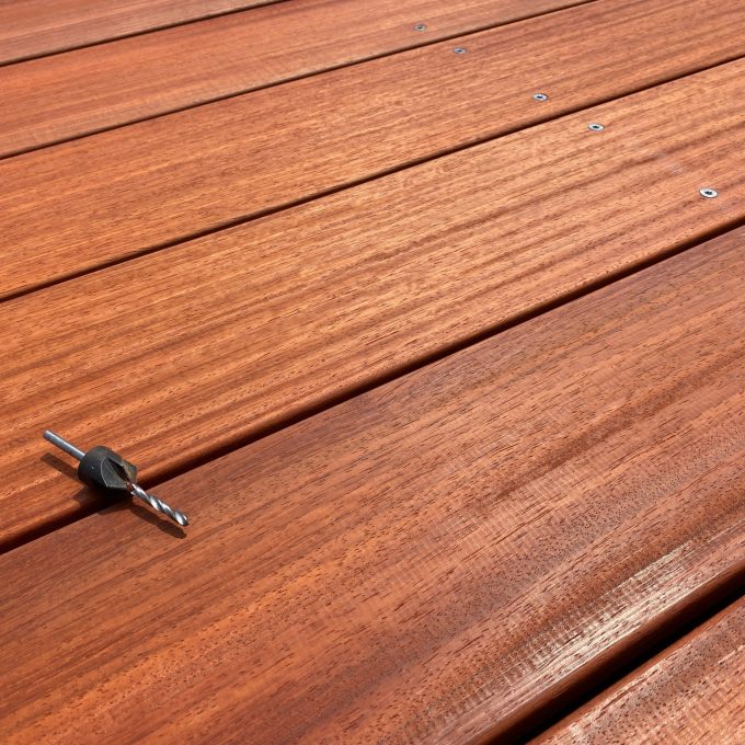 Foreuse sur lames de terrasse en bois rouge, pose de platelage