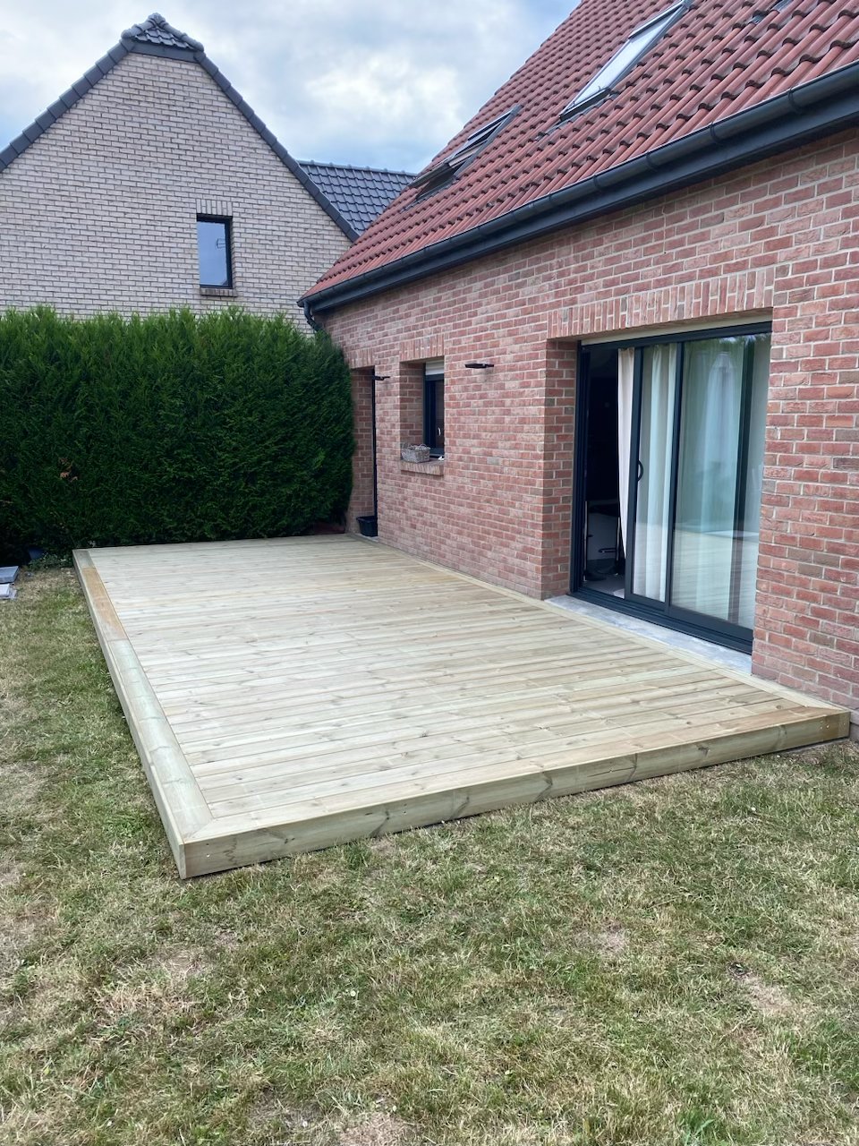 Terrasse en pin sylvestre autoclave classe 3 devant une maison en brique
