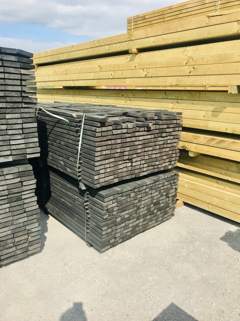 Poteaux et lames de bois en pin sylvestre coeur rouge stockés en extérieur, palettes de lames grisées