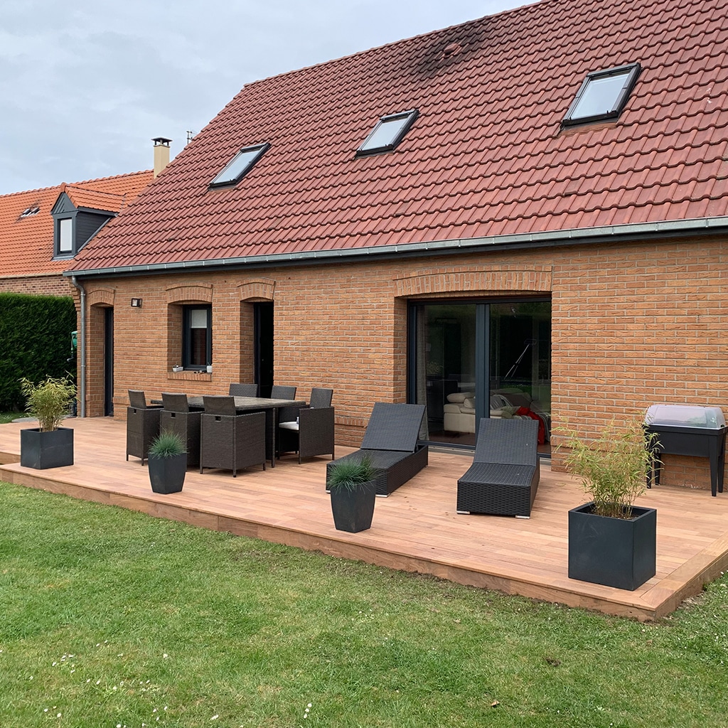 Terrasse en bois spacieuse devant une maison en brique avec mobilier de jardin
