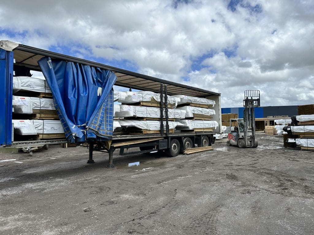 Expédition de bois sur parc extérieur, semi-remorque chargée de paquets emballés et chariot élévateur