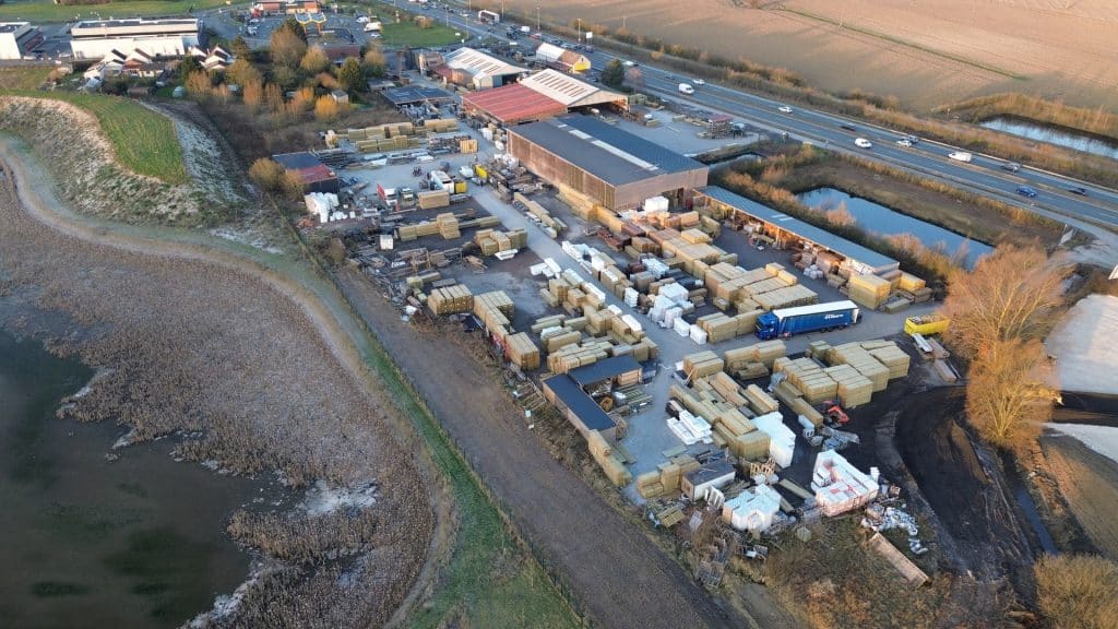 Vue aérienne du site de production avec hangars, stock de palettes et étang à Illies